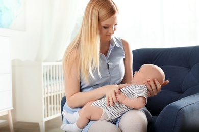 Happy mother with her baby sitting in armchair at home