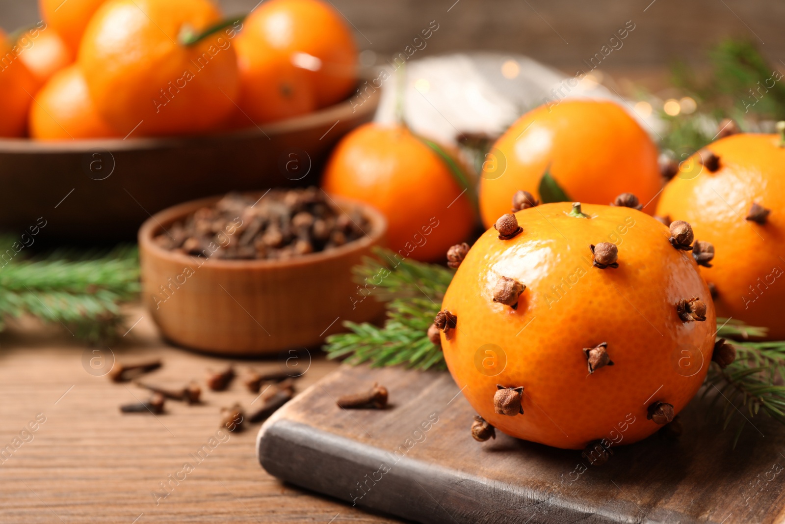 Photo of Delicious fresh tangerines with cloves on wooden table, closeup. Christmas celebration