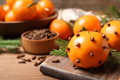 Delicious fresh tangerines with cloves on wooden table, closeup. Christmas celebration