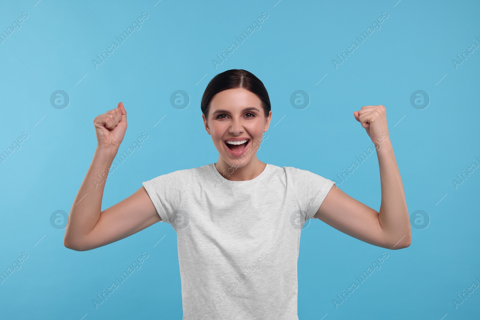 Photo of Emotional sports fan celebrating on light blue background