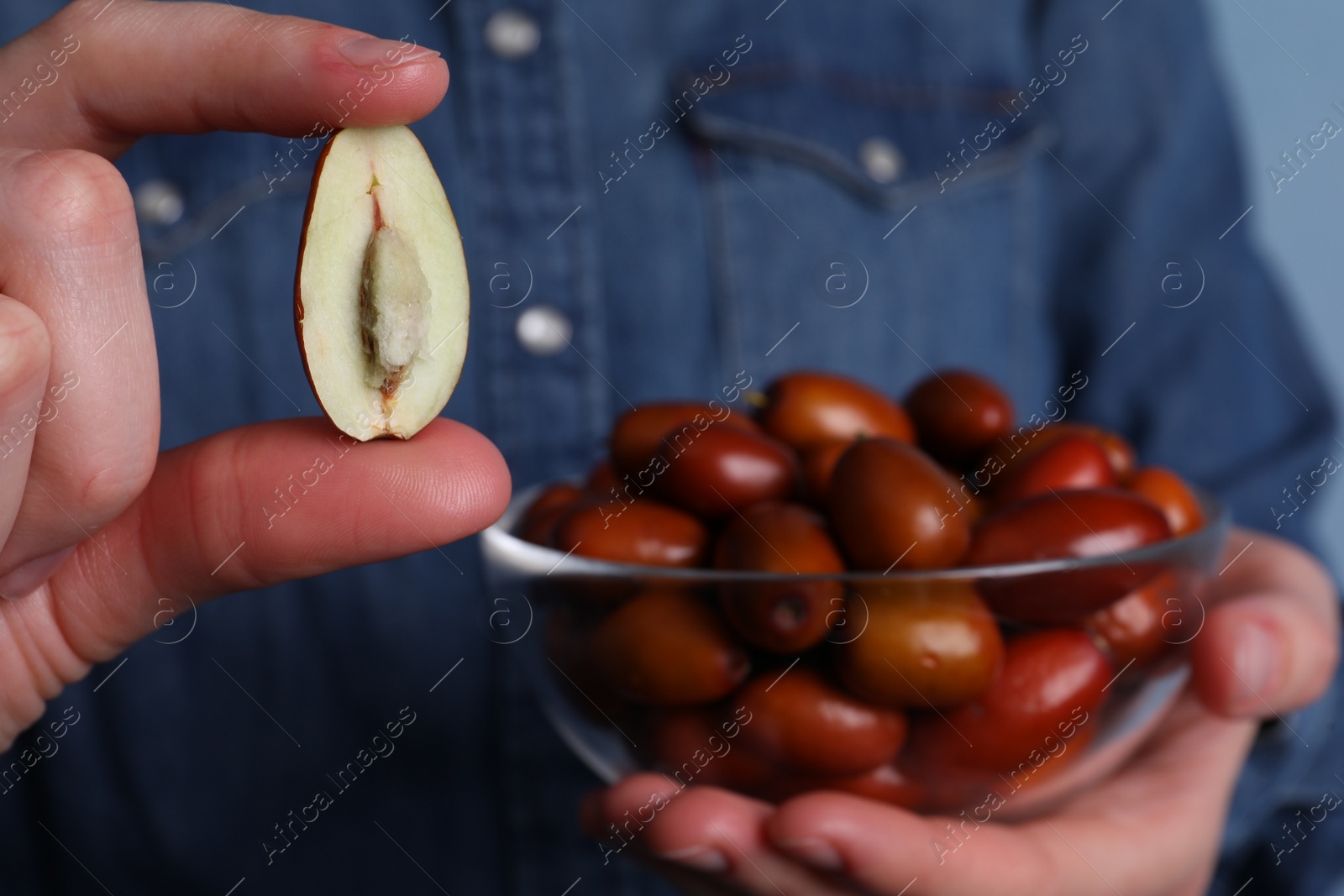 Photo of Woman holding half of fresh Ziziphus jujuba fruit, closeup