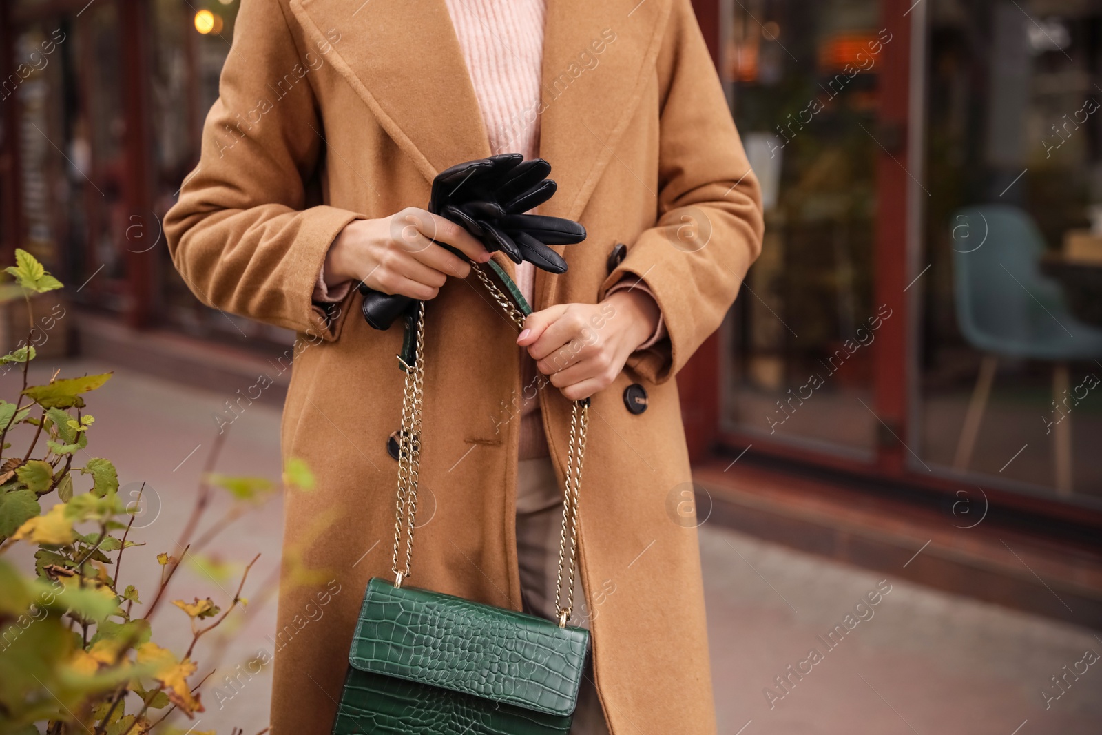 Photo of Young woman holding black leather gloves, closeup. Stylish clothes