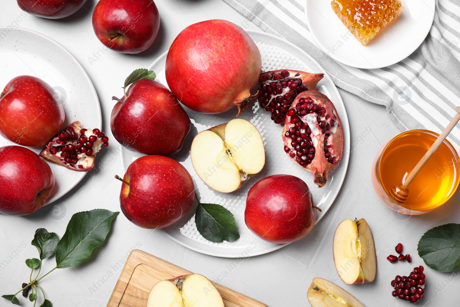 Photo of Honey, apples and pomegranates on light table, flat lay. Rosh Hashanah holiday