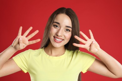 Photo of Woman in yellow t-shirt showing number eight with her hands on red background
