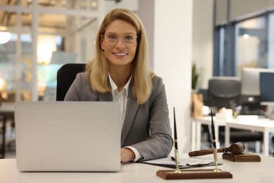 Photo of Smiling lawyer working with laptop at table in office