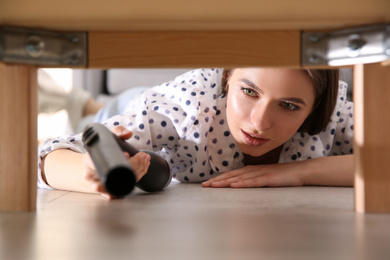 Young woman using vacuum cleaner at home