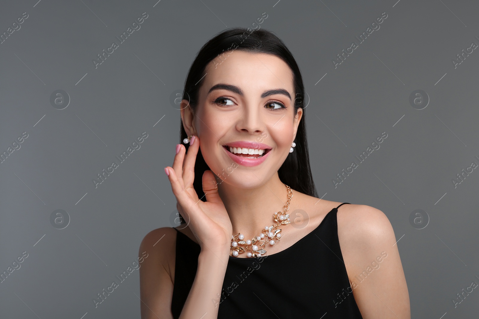 Photo of Beautiful young woman with elegant jewelry on dark grey background