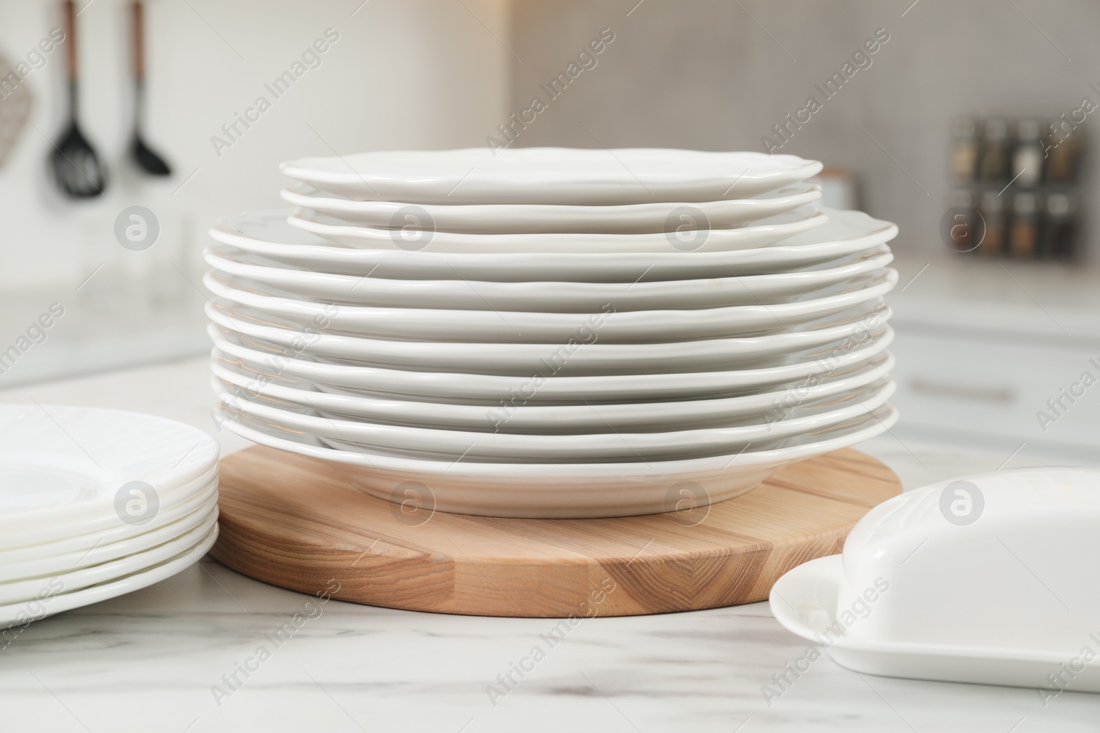 Photo of Clean plates and butter dish on white marble table in kitchen