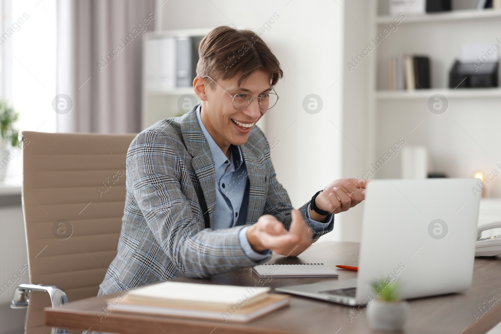 Photo of Man using video chat during webinar at wooden table in office