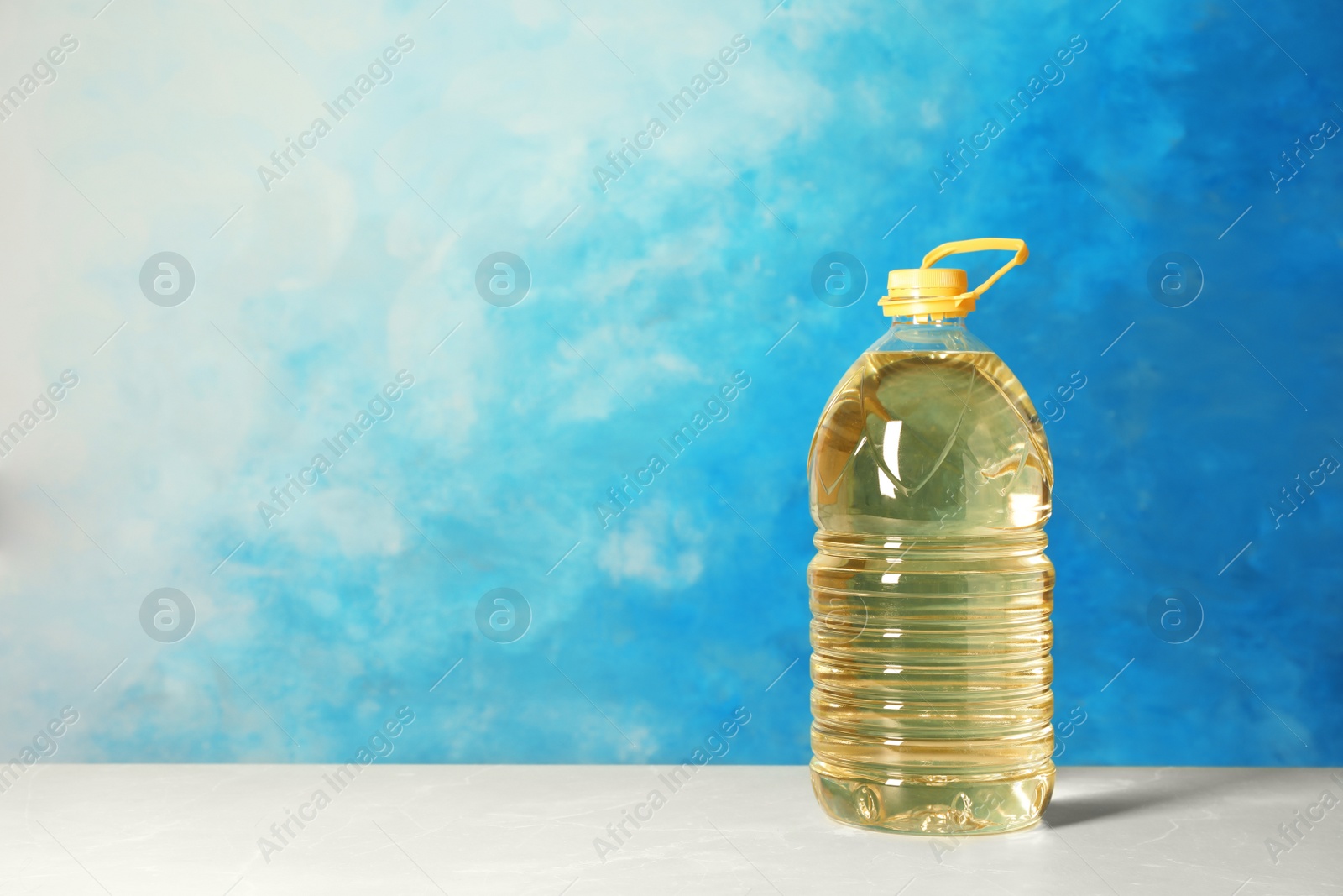 Photo of Bottle of oil on table against color background. Space for text