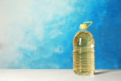 Bottle of oil on table against color background. Space for text