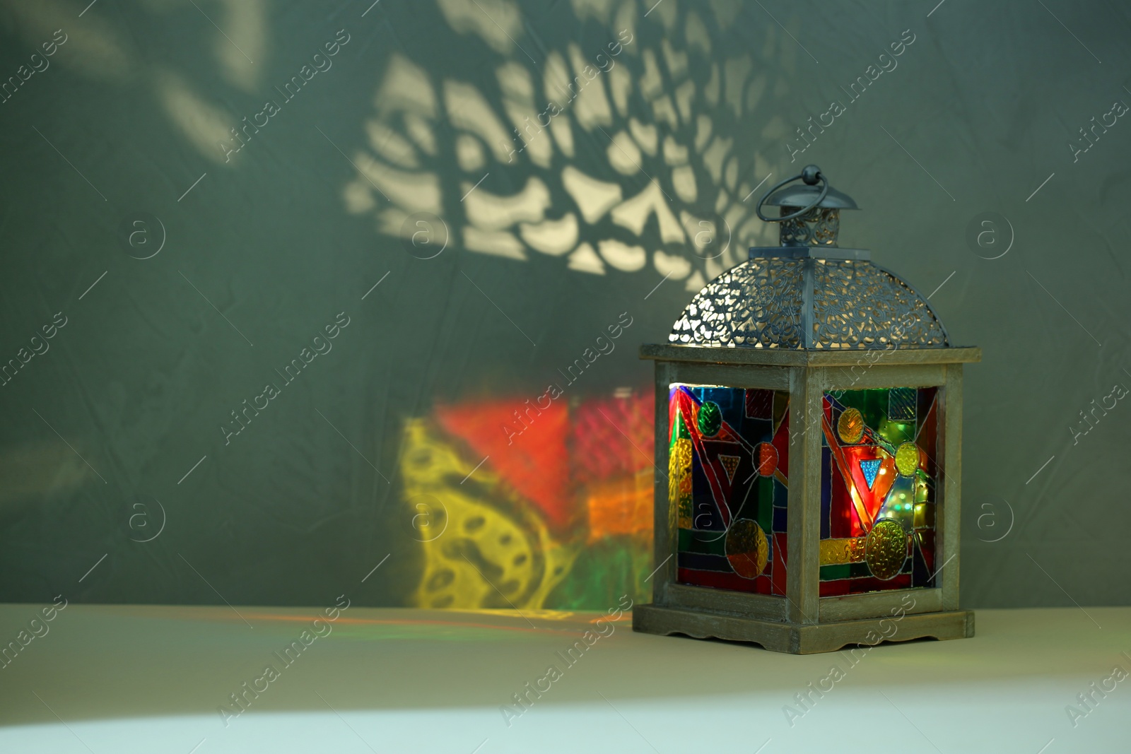 Photo of Decorative Arabic lantern on table against dark background. Space for text