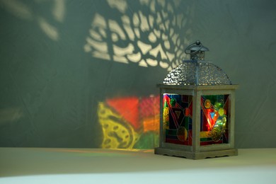 Decorative Arabic lantern on table against dark background. Space for text