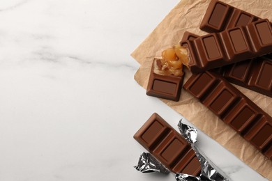 Photo of Tasty chocolate bars on white table, flat lay. Space for text