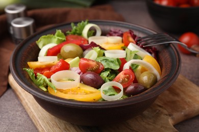 Photo of Bowl of tasty salad with leek and olives on brown table, closeup