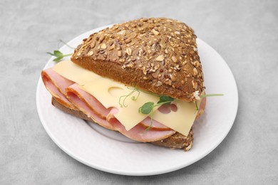 Photo of Delicious sandwich with ham and cheese on light gray table, closeup