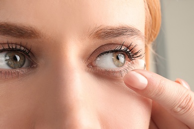 Photo of Young woman putting contact lens in her eye, closeup