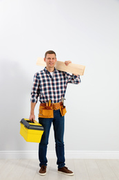 Handsome carpenter with wooden planks near light wall