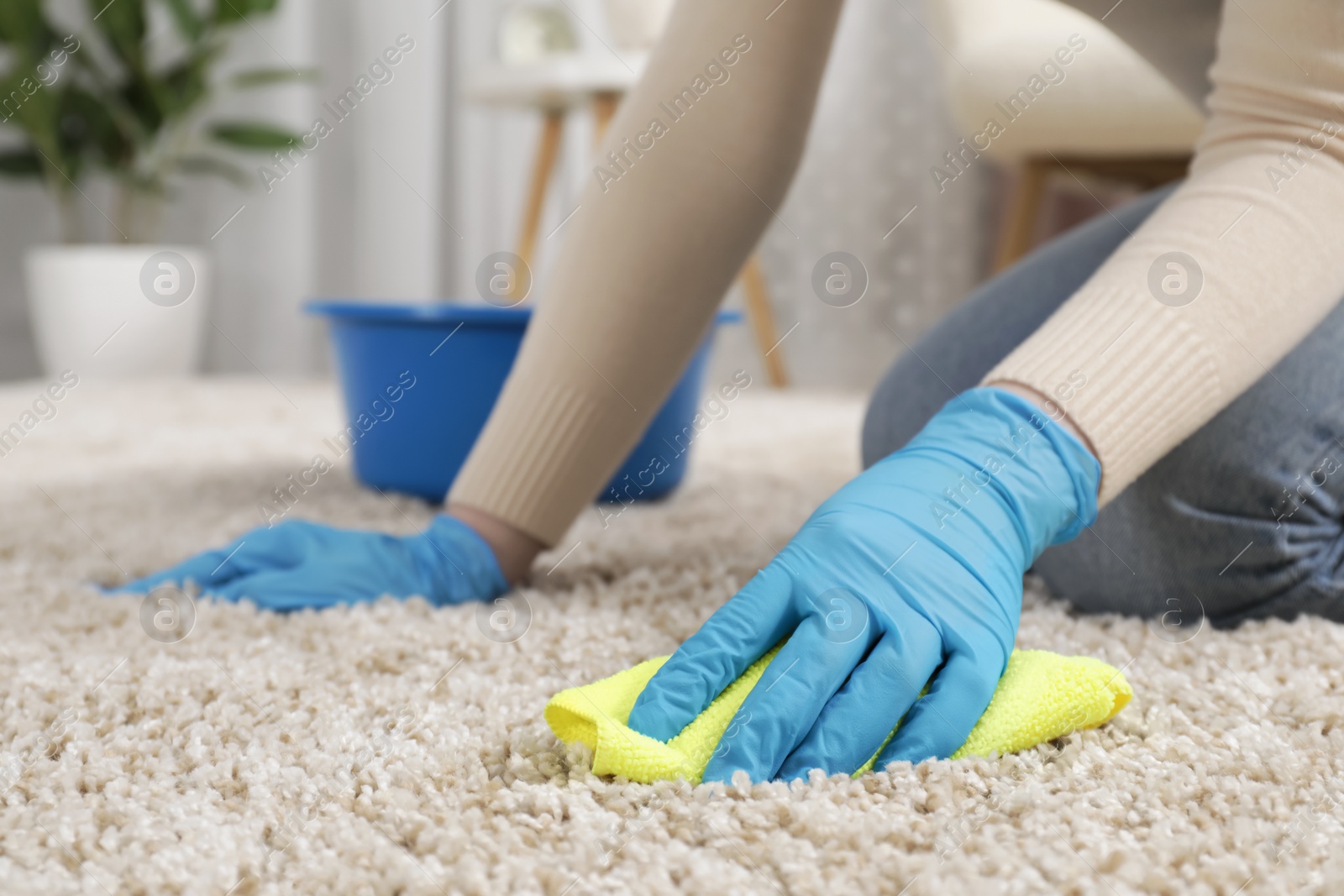 Photo of Woman in rubber gloves cleaning carpet with rag indoors, closeup. Space for text