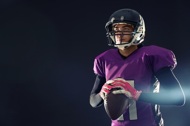 Photo of American football player on dark background. Space for text