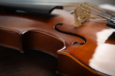 Photo of Beautiful violin on wooden table, closeup view