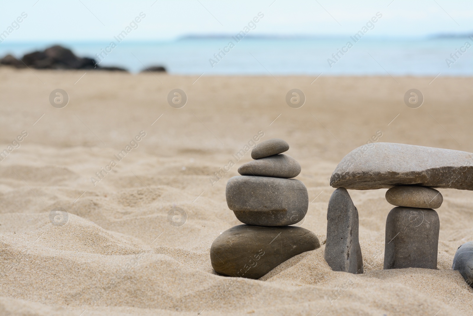 Photo of Stacks of stones on beautiful sandy beach near sea, space for text