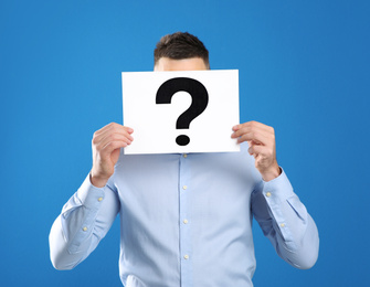 Photo of Man holding paper with question mark on blue background