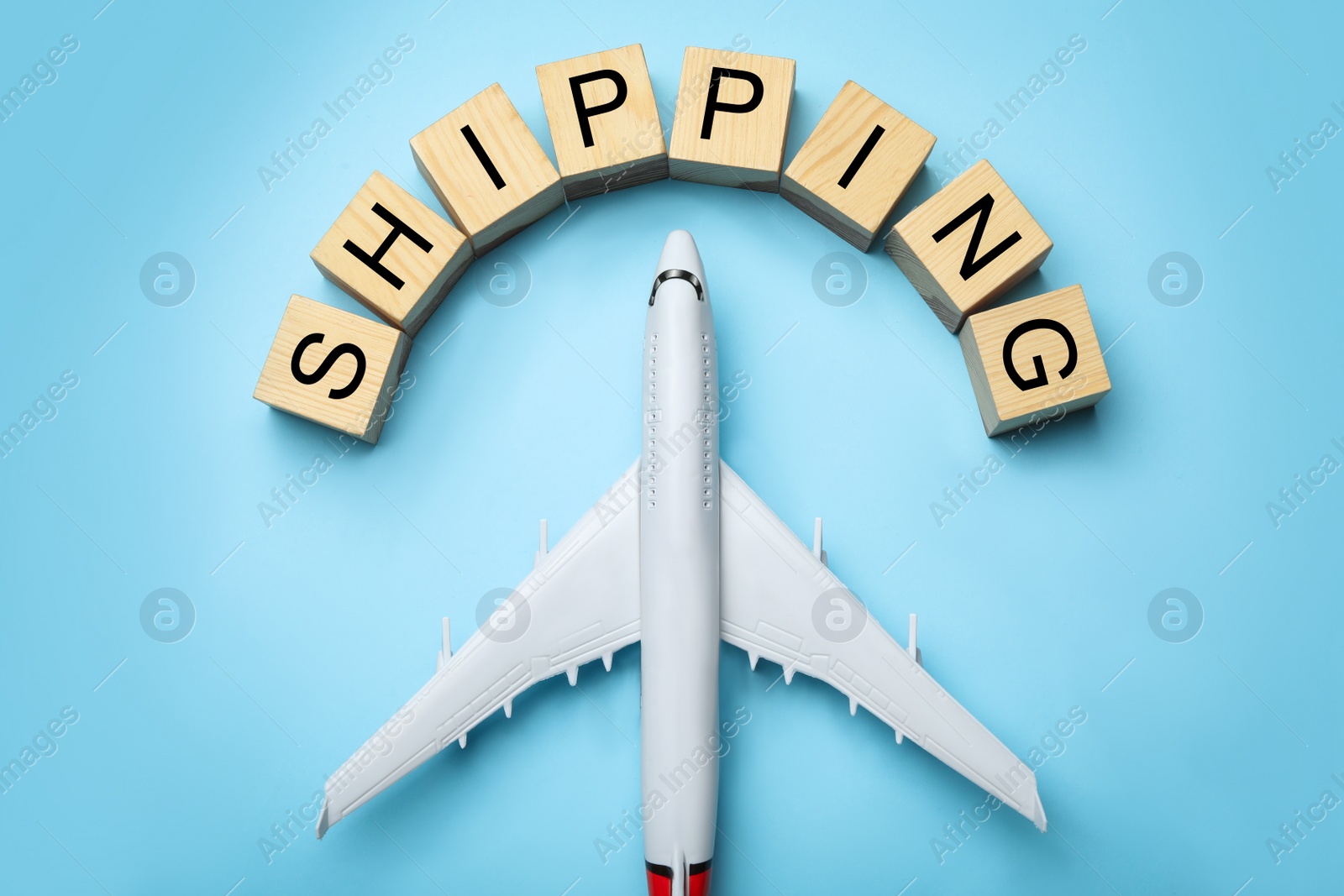 Photo of Toy plane with word SHIPPING on blue background, flat lay. Logistics and wholesale concept