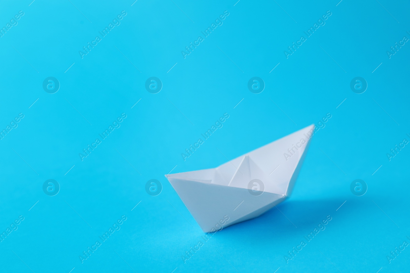 Photo of Handmade white paper boat on light blue background. Space for text