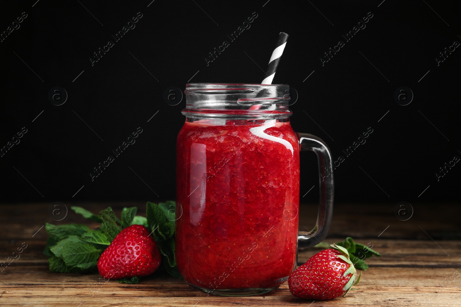 Photo of Tasty strawberry smoothie and mint on wooden table