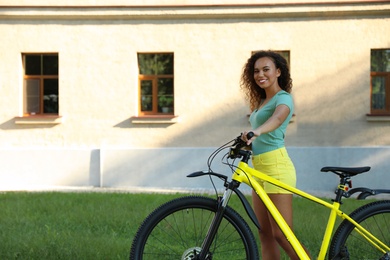 Beautiful young African-American woman with bicycle on city street