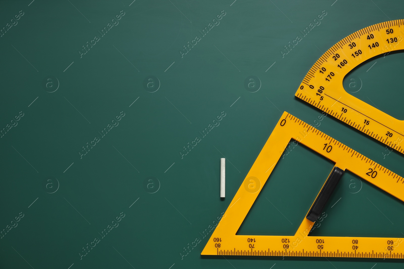 Photo of Protractor, triangle and chalk on green chalkboard, flat lay. Space for text