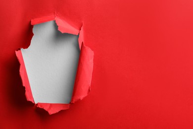 Photo of Hole in red paper on white background, space for text