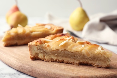 Board with pieces of delicious sweet pear tart on table, closeup