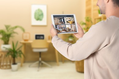 Man using smart home security system on tablet computer indoors, closeup. Device showing different rooms through cameras