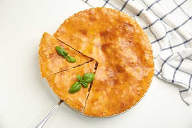 Photo of Delicious pie with meat and basil on white table, flat lay