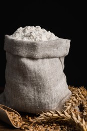 Photo of Wheat flour in sack bag, spikes and grains on wooden table