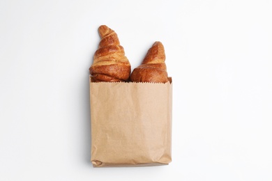 Photo of Paper bag with croissants on white background, top view. Space for design