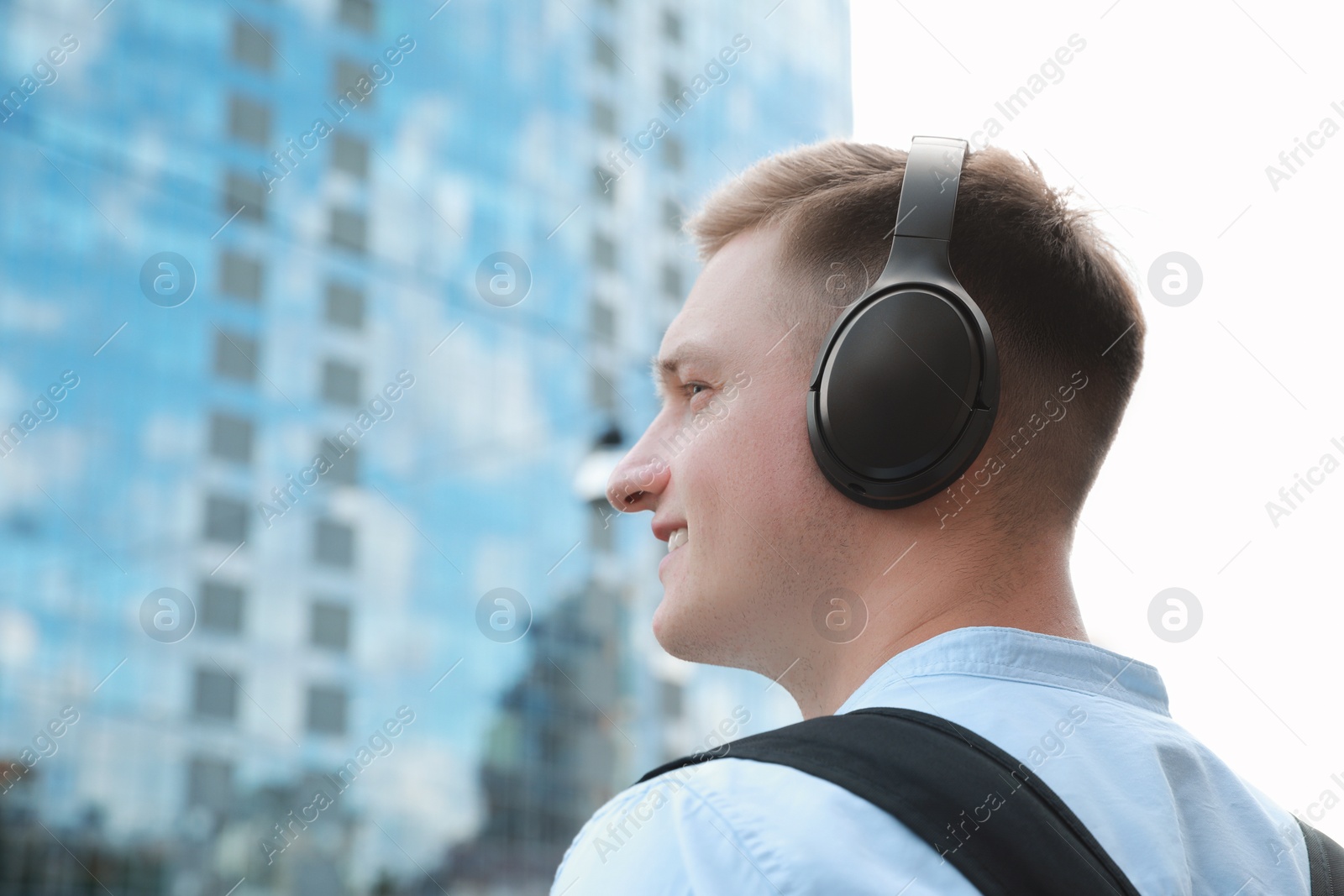 Photo of Smiling man in headphones listening to music outdoors. Space for text