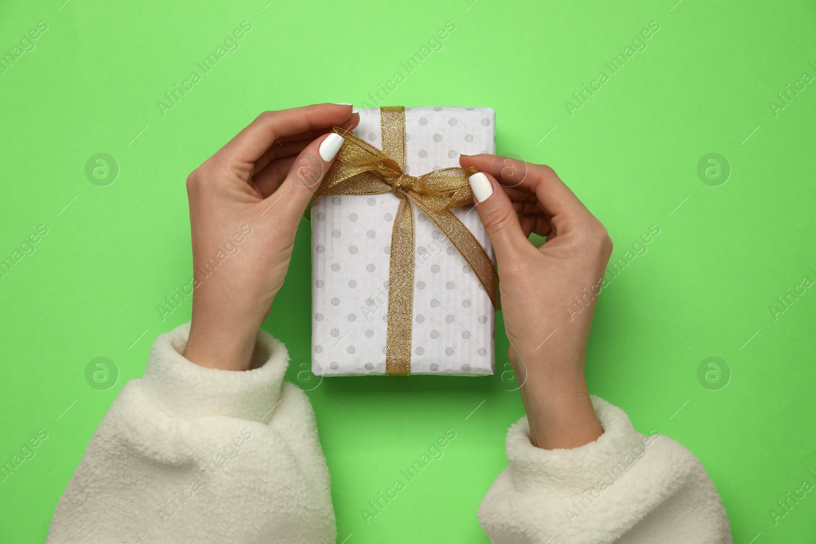 Photo of Woman holding Christmas gift on green background, closeup