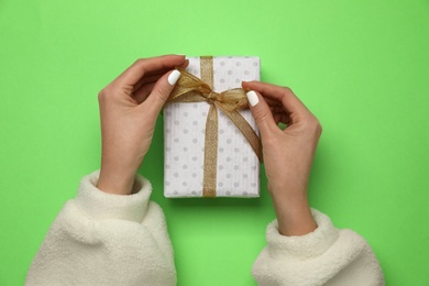 Woman holding Christmas gift on green background, closeup