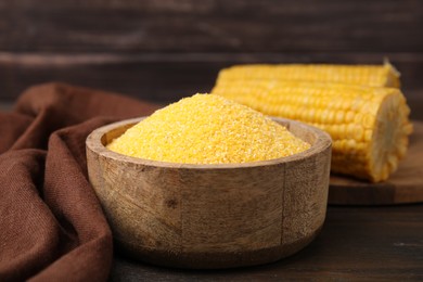 Photo of Raw cornmeal in bowl on wooden table, closeup