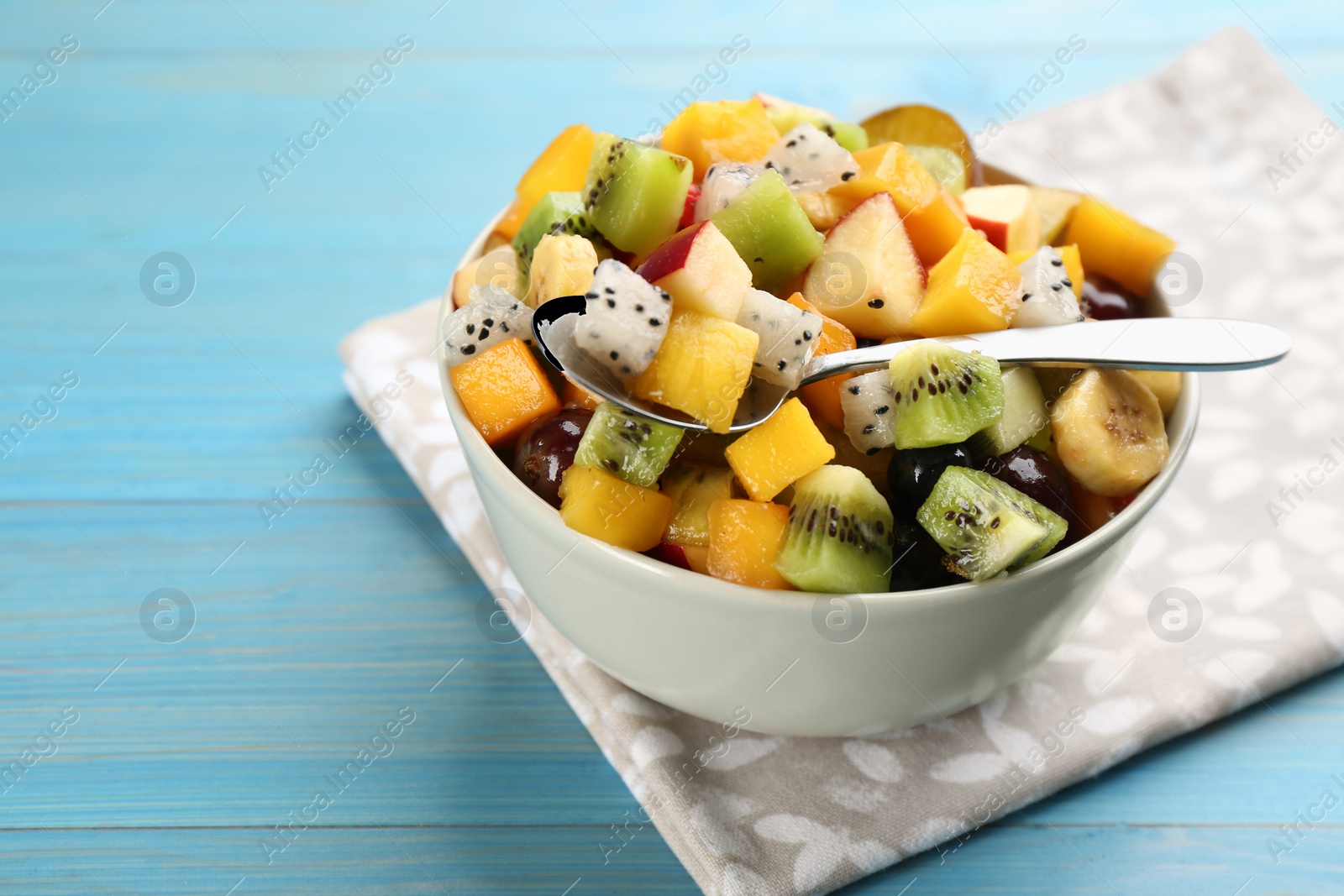 Photo of Delicious exotic fruit salad on light blue wooden table