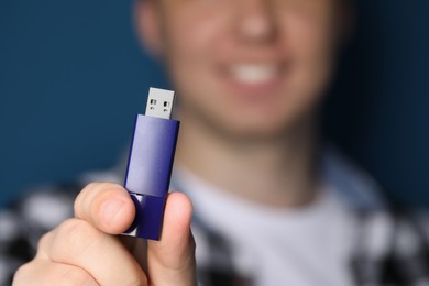 Photo of Man with usb flash drive on blue background, closeup. Space for text