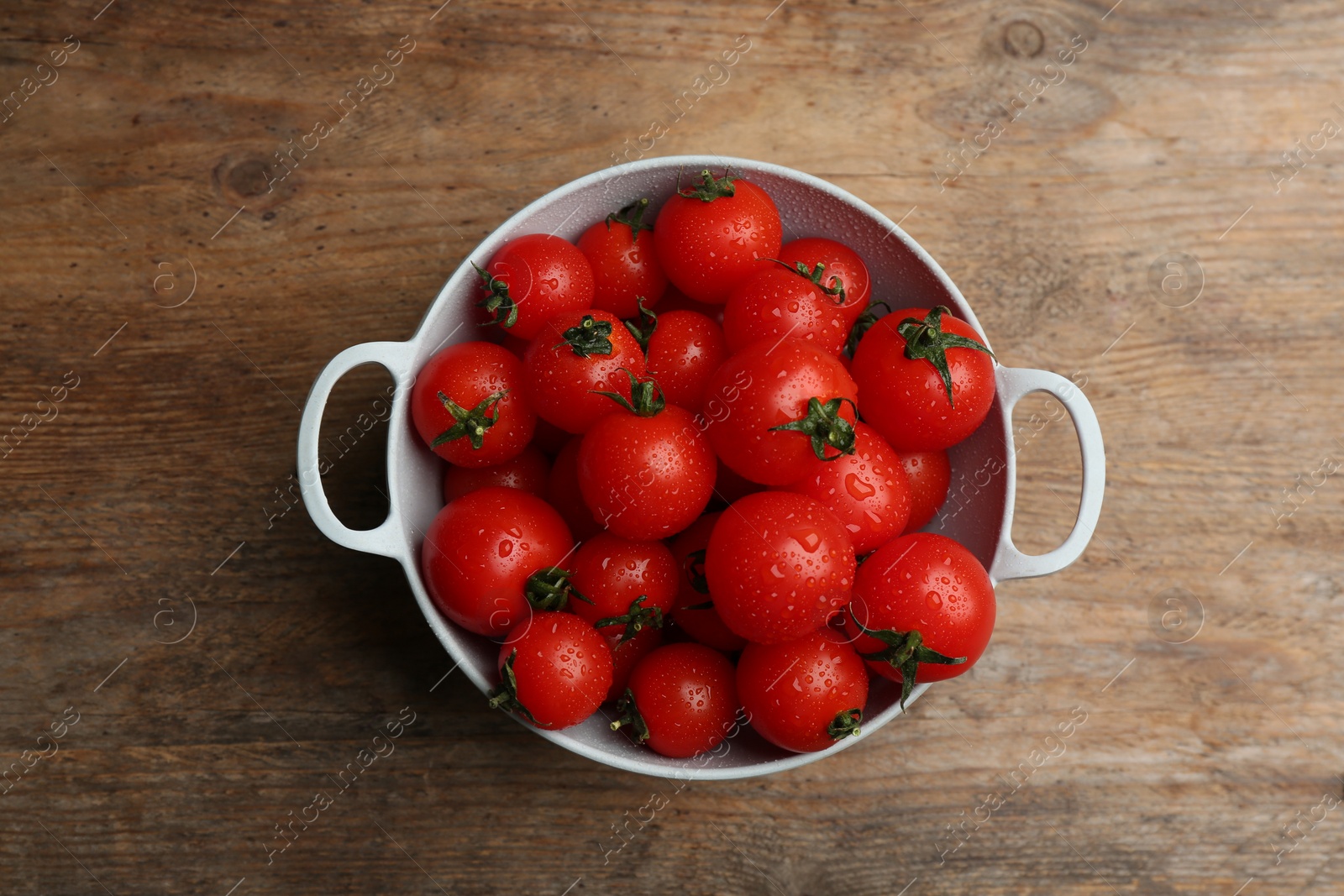 Photo of Fresh ripe cherry tomatoes with water drops on wooden table, top view