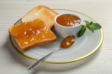 Delicious toasts served with jam and mint on white wooden table, closeup