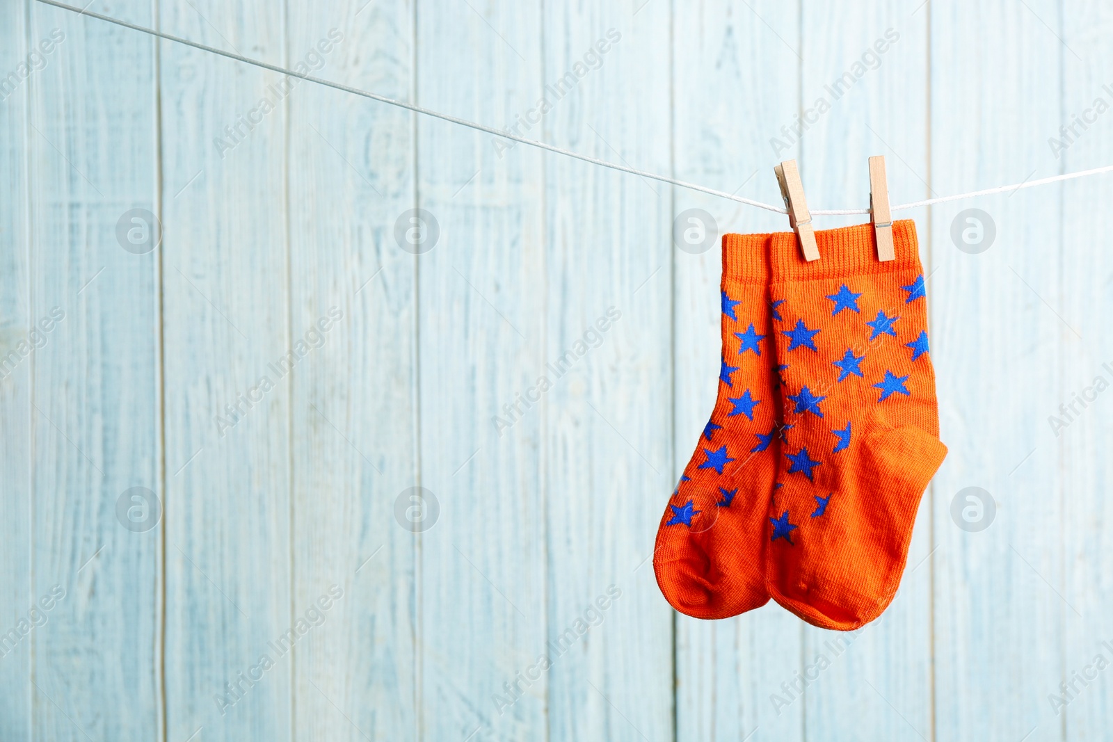 Photo of Pair of socks on laundry line against wooden background, space for text. Baby accessories