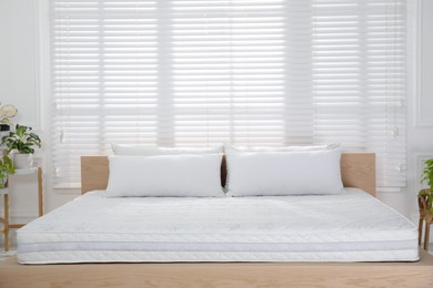 Wooden bed with soft white mattress and pillows in cozy room interior