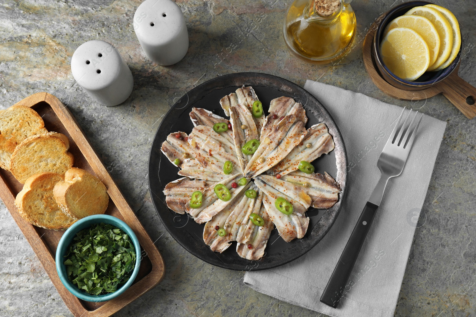 Photo of Tasty pickled anchovies served on textured table, flat lay