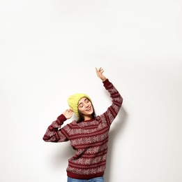 Young woman in warm sweater and knitted hat on white background. Celebrating Christmas